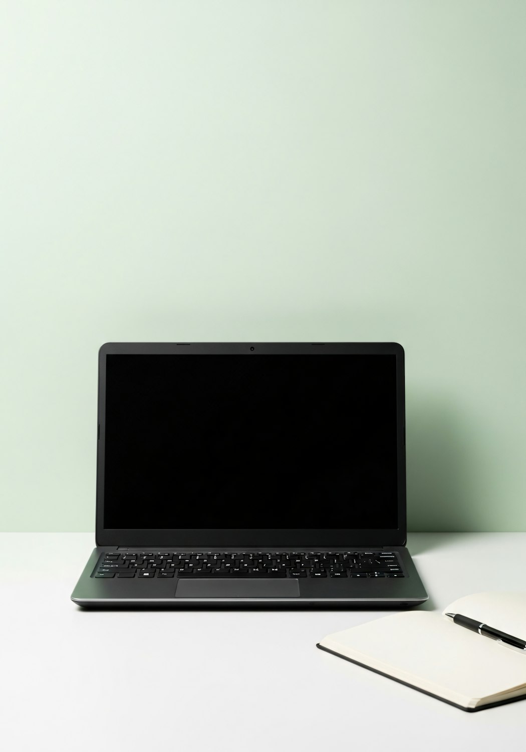 Minimalist desk with a laptop, notebook and pen, used to illustrate adding a logo to a website